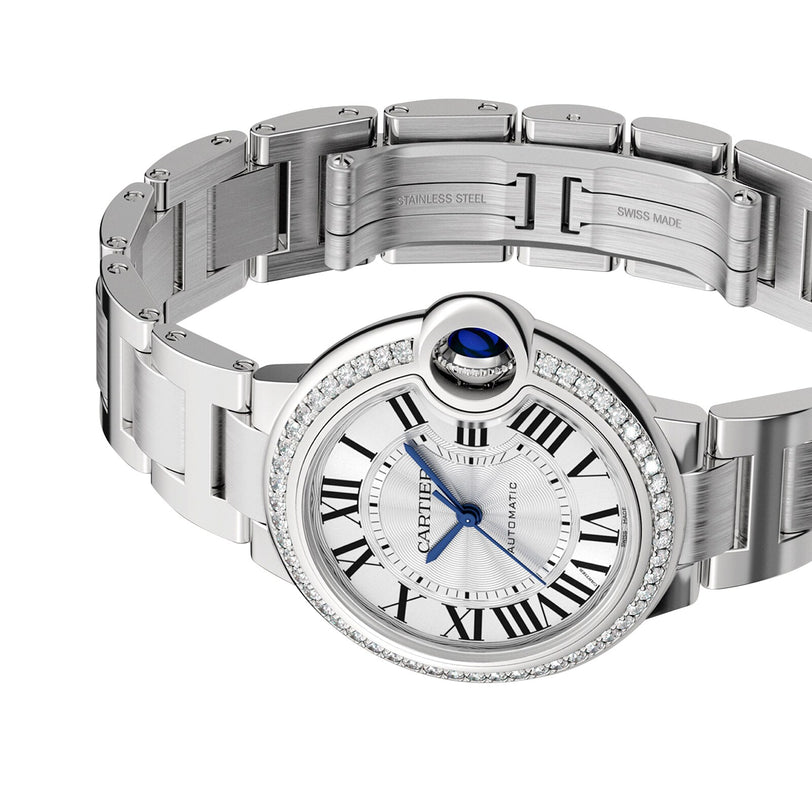 The Ballon Bleu de Cartier watch features a round silver face, Roman numerals, blue hands, a diamond bezel, and a classic steel case bracelet—an elegant timepiece by Cartier.
