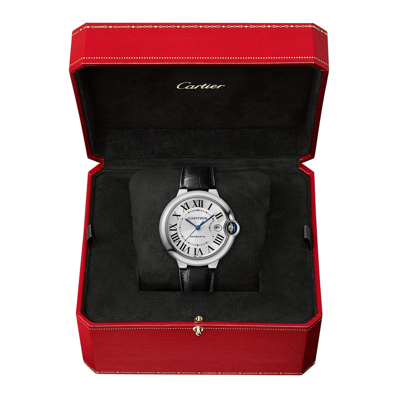 A Cartier Ballon Bleu de Cartier wristwatch with a black leather strap and Roman numerals is shown in an open red Cartier box with a black velvet interior, highlighting its elegant mechanical movement.