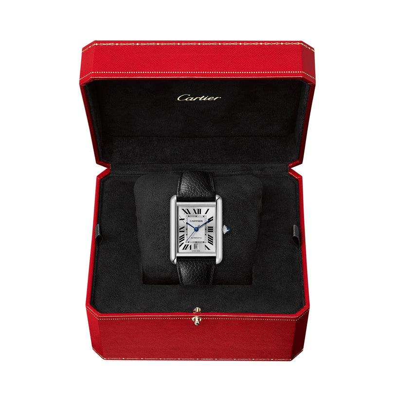 The Cartier Tank Must de Cartier wristwatch with a rectangular face, silvered dial, and black calfskin strap is displayed in an open red Cartier box with a black interior.