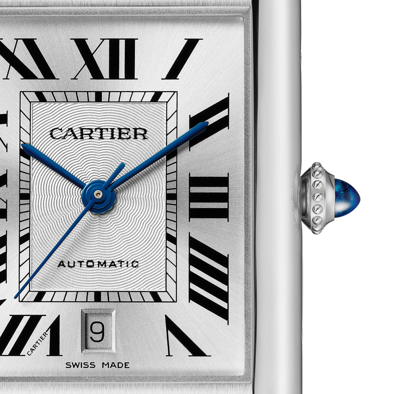 Close-up of the Cartier Tank Must de Cartier watch, featuring Roman numerals, blue hands, a date window at 6 o’clock, silvered flinqué dial with textured square center, and an elegant black calfskin strap.