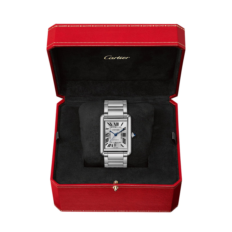 A silver Cartier Tank Américaine watch with a rectangular face, silvered flinqué dial, and Roman numerals is shown in an open red Cartier box with a black interior.