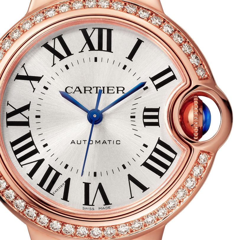 Close-up of the Cartier Ballon Bleu de Cartier watch in rose gold, showcasing a round diamond-set bezel, Roman numerals, blue hands, automatic movement, and a blue cabochon crown. The dial reads CARTIER and AUTOMATIC.