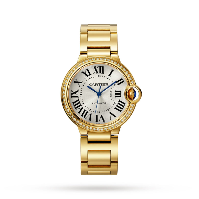 A Cartier Ballon Bleu de Cartier wristwatch, featuring a round face with Roman numerals, blue hands, diamond-set bezel, and yellow gold linked bracelet, is elegantly displayed on a white background.