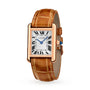 The Cartier Tank Louis Cartier watch features a rectangular rose gold case, brown alligator strap, white dial with black Roman numerals, blue hands, and a blue stone-set crown.