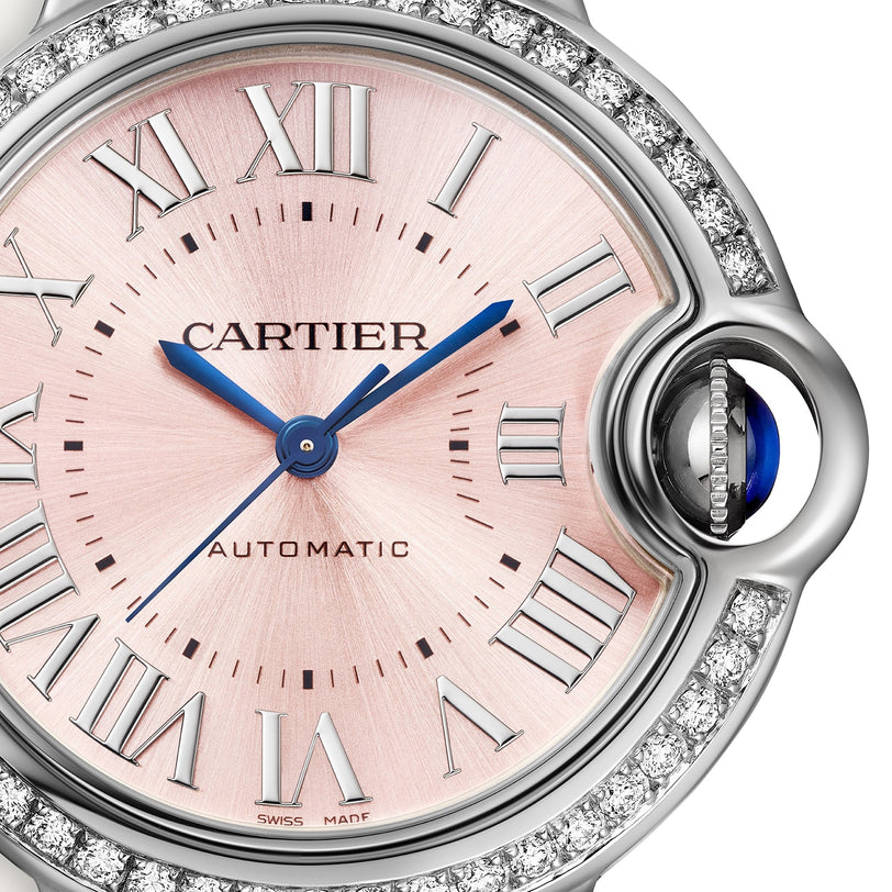 Close-up of the Ballon Bleu de Cartier watch by Cartier, featuring a pink sunray dial, Roman numerals, blue hands, diamond-set bezel, and a signature sapphire cabochon crown.