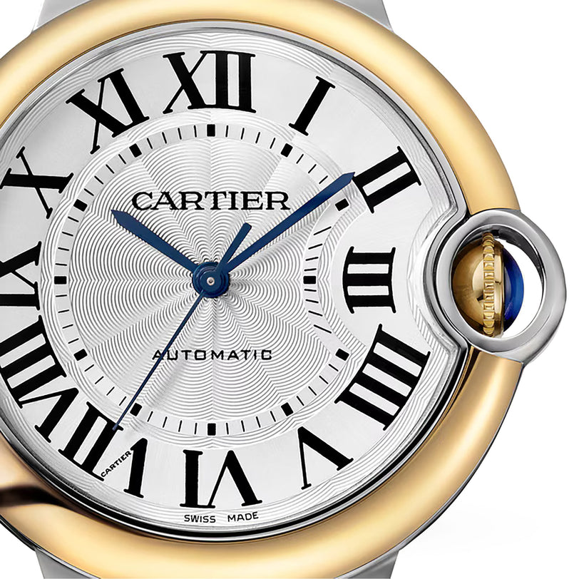 Close-up of a Ballon Bleu de Cartier watch face featuring Roman numerals, blue steel hands, Automatic label, and an 18K yellow gold and silver case with signature crown at 3 oclock. Brand: Cartier.