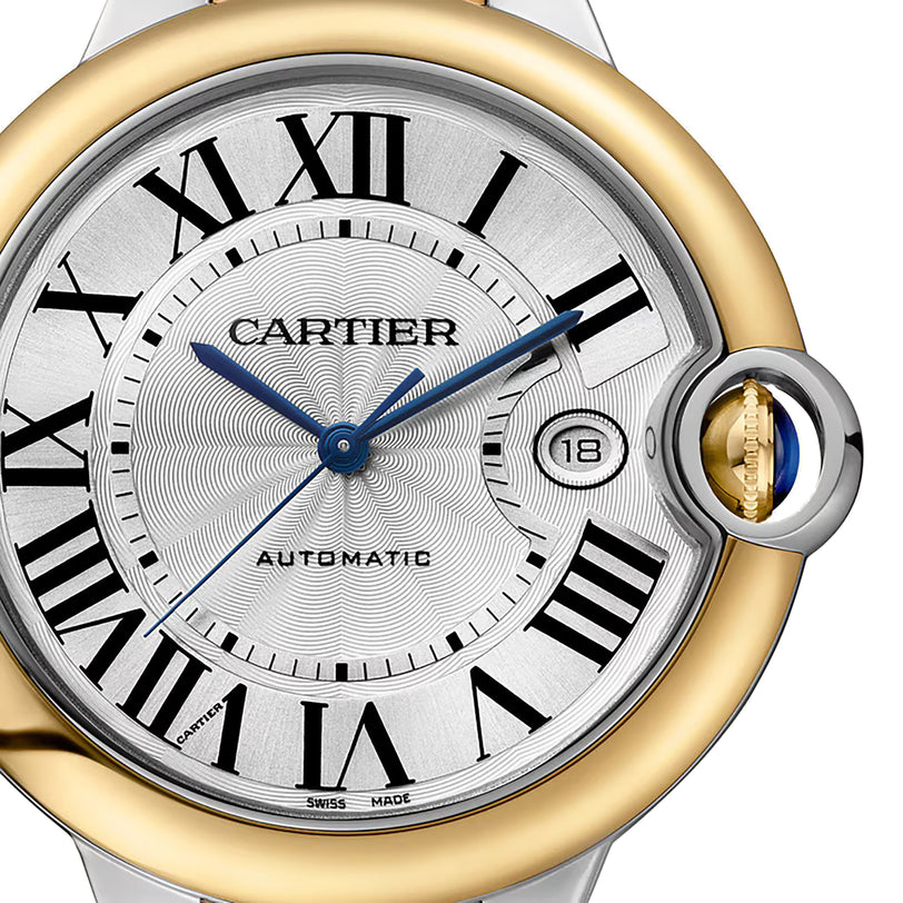 Close-up of the Cartier Ballon Bleu de Cartier watch face featuring Roman numerals, 18K yellow gold and silver bezel, blue hands, date window at 3 o’clock, and AUTOMATIC text for its Calibre 1847 MC automatic movement.