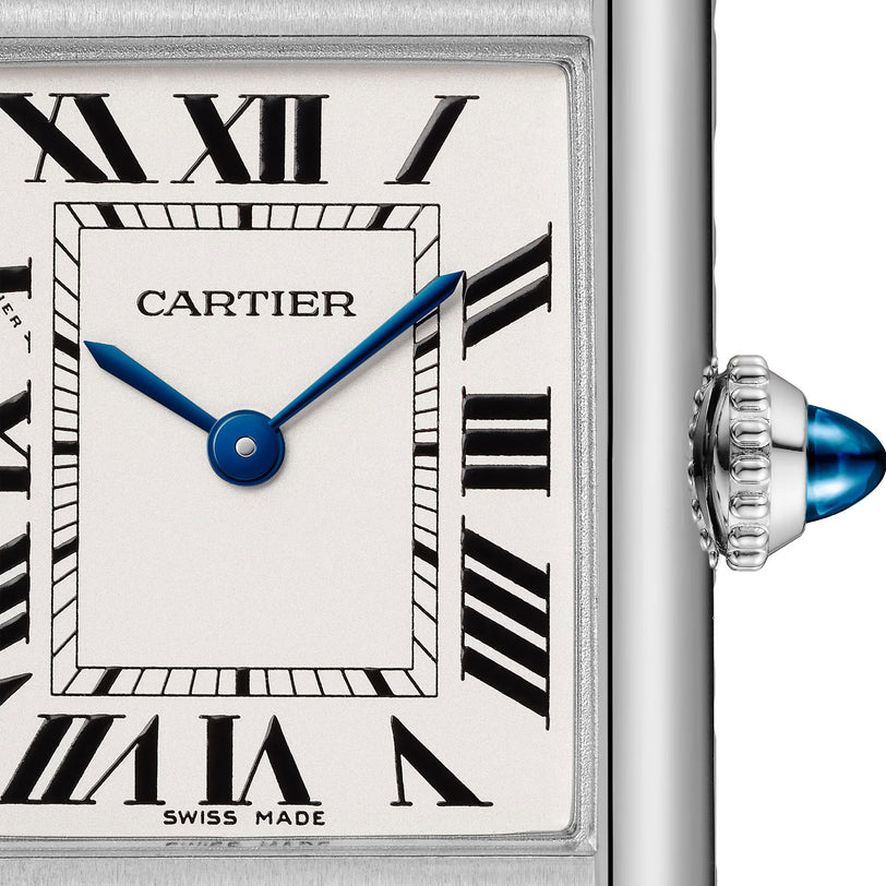 Close-up of a Cartier Tank Must de Cartier watch face featuring Roman numerals, blue hands at 10:10, and a silver crown with a blue cabochon.