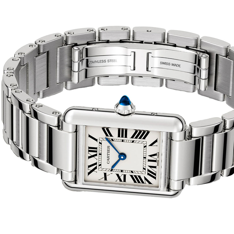 The Tank Must de Cartier, by Cartier, is a stainless steel watch featuring a square silvered dial, Roman numeral markers, quartz movement, and a blue jewel on the crown, pictured with its clasp open.