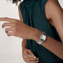 A person in a sleeveless dark green top wears a Cartier Panthère de Cartier jewellery watch with a rectangular face on their left wrist.