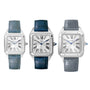 Three Cartier Santos-Dumont watches, each with a silver square face, Roman numerals, and a unique leather strap color: light blue, dark blue, or grey.