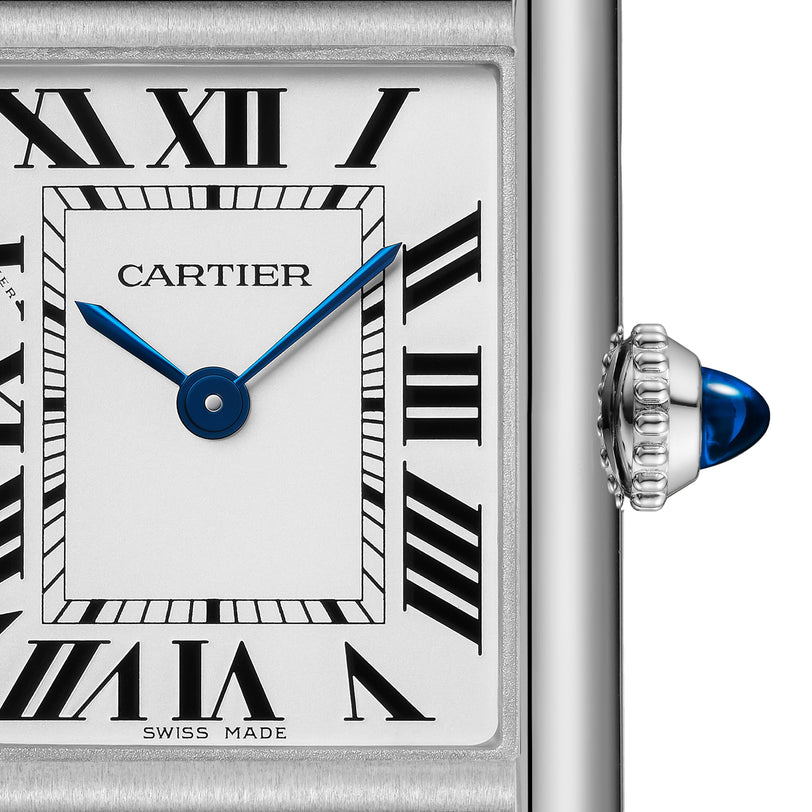 Close-up of Cartier’s Tank Must Solarbeat™ watch face, featuring Roman numerals, blue hands, a silvered dial, and a right-side crown adorned with a blue cabochon gemstone.