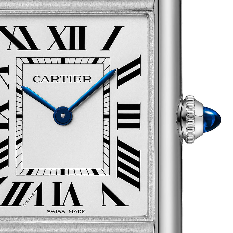 Close-up of the Cartier Tank Must Solarbeat™ watch face featuring black Roman numerals, blue hands, a silver steel bezel, and a crown adorned with a blue cabochon.