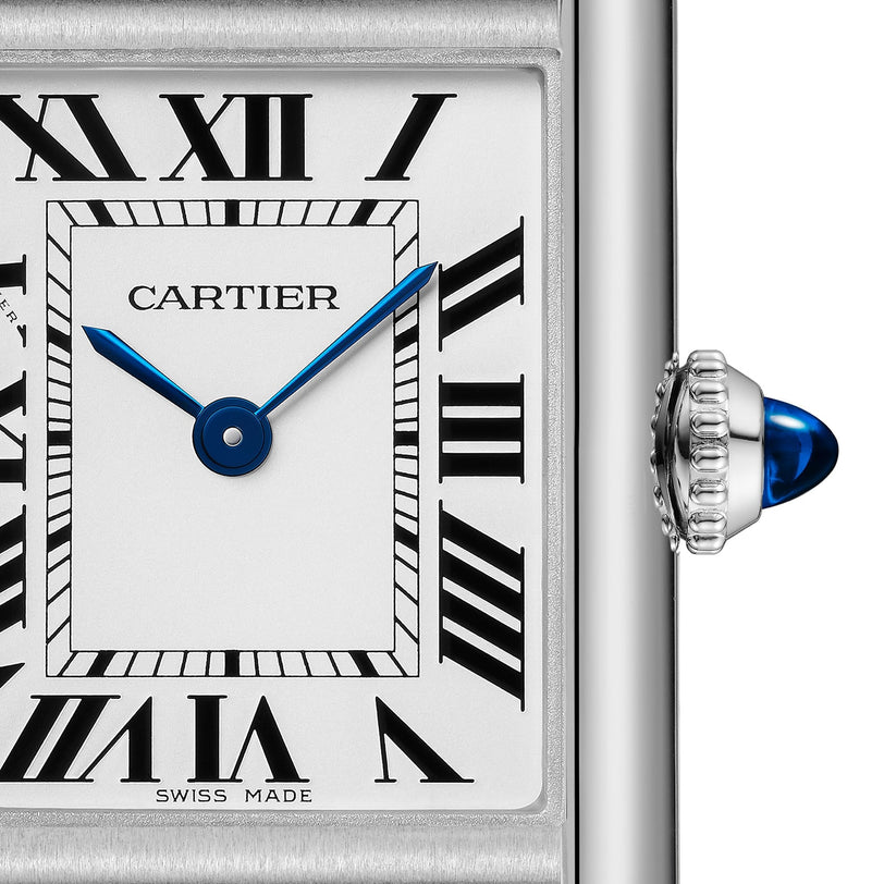 Close-up of a Cartier Tank Must Solarbeat™ watch face featuring Roman numerals, blue sword-shaped hands, a steel case, and a crown adorned with a blue cabochon.