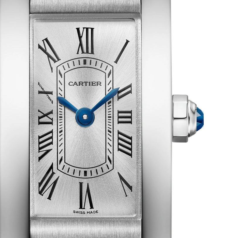 Close-up of the Cartier Tank Américaine watch, showcasing blue hands, Roman numerals, a silver dial, and a crown adorned with a blue cabochon.