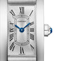 Close-up of the Cartier Tank Américaine watch, showcasing blue hands, Roman numerals, a silver dial, and a crown adorned with a blue cabochon.