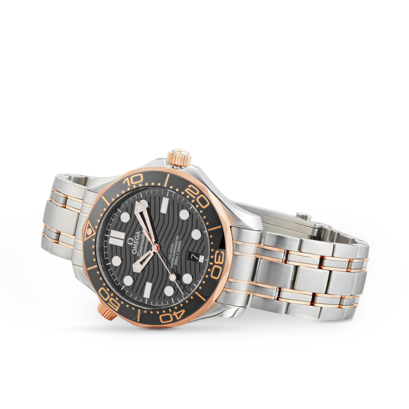 The OMEGA Seamaster Diver 300M wristwatch features a silver and rose gold case, black dial with white markers, and a metal bracelet—an elegant Co-Axial timepiece inspired by James Bonds refined style, shown on a white background.