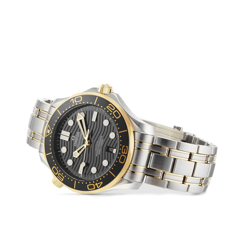 An OMEGA Seamaster Diver 300M in two-tone stainless steel and gold with a black dial, gold accents, and a metal link bracelet, shown at an angle on a white background.