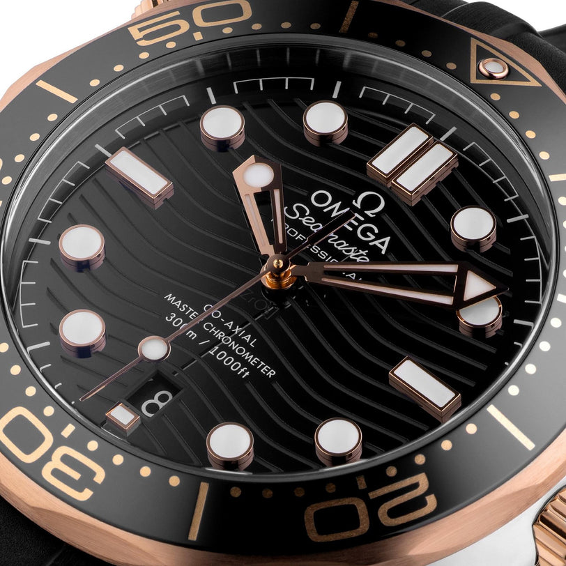 Close-up of the OMEGA Seamaster Diver 300M watch with a black wave-patterned dial, Ceragold bezel and markers, and a date window at 6 o’clock. This luxury Master Chronometer showcases OMEGA’s precision craftsmanship.