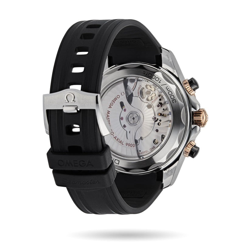 A close-up of the back of an OMEGA Seamaster Diver 300M watch shows its transparent case revealing the movement, black rubber strap, and metal clasp with the OMEGA logo.