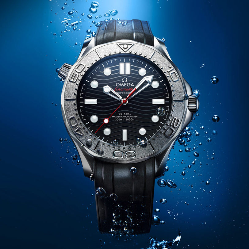 A close-up of the OMEGA Seamaster Diver 300M Nekton Edition watch with a black strap, seen underwater with bubbles around its stainless steel case.