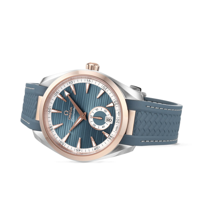 The OMEGA Seamaster Aqua Terra 150M is a wristwatch with a blue textured strap, blue dial, rose gold accents, date subdial at an angle, and Master Chronometer precision.