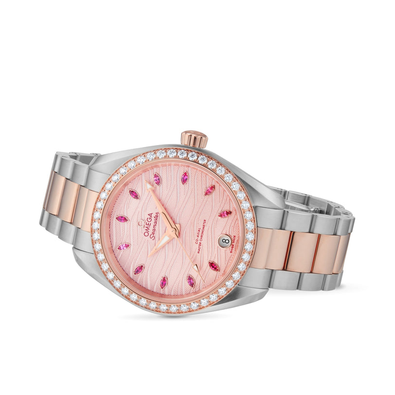 The OMEGA Seamaster Aqua Terra 150M ladies watch features a two-tone metal band, pink textured dial, diamond bezel, pink gemstone hour markers, and a date window at 6 o’clock.