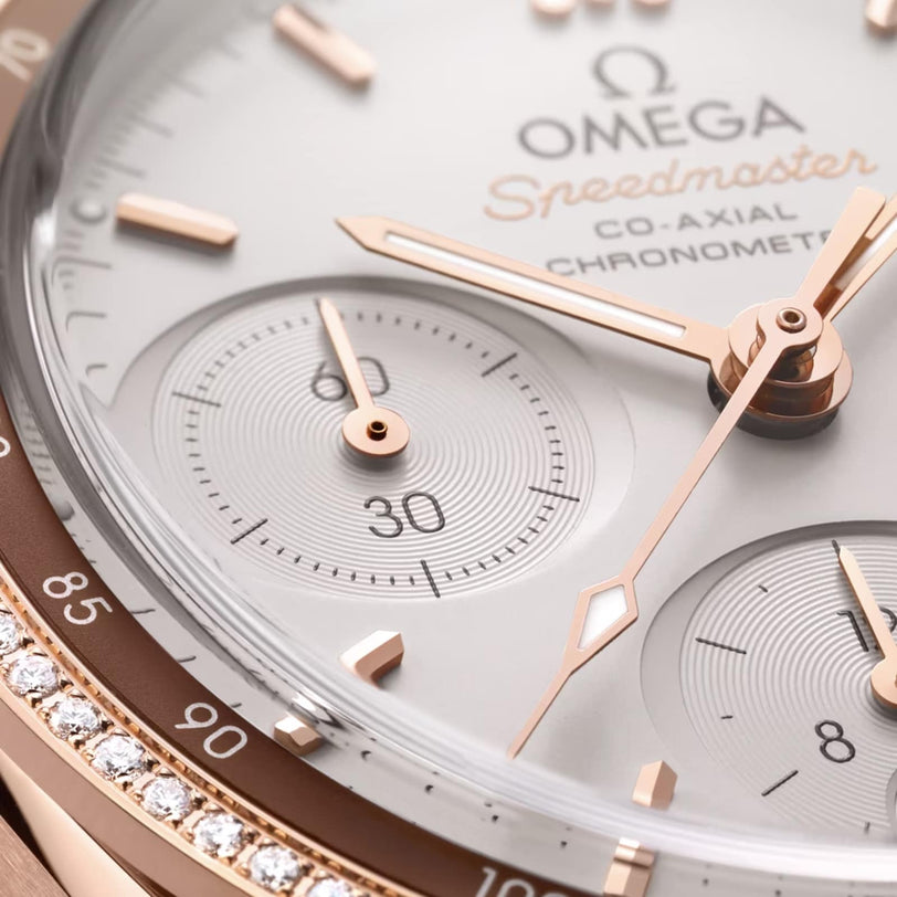 Close-up of the OMEGA Speedmaster 38 watch face, featuring 18K Sedna™ gold hands, chronograph dials, a diamond-set bezel, and powered by the Co-Axial Calibre 3330.
