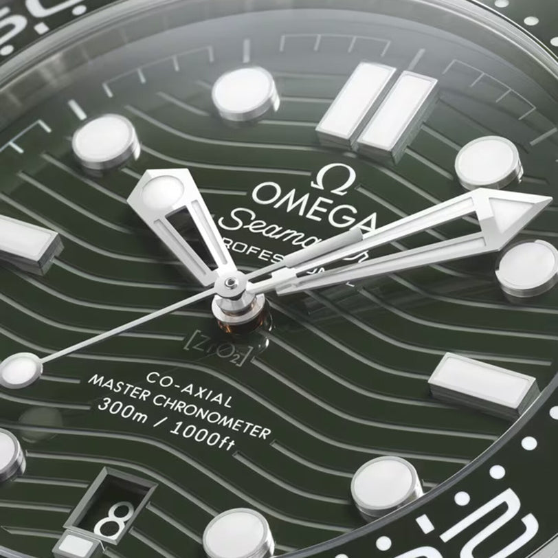 Close-up of the OMEGA Seamaster Diver 300M watch face, featuring white hands and markers, a green wavy-patterned dial, Master Chronometer certification, water resistance info, and a date window at 6 oclock.