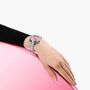 A person in a black sleeve rests their hand on a pink surface, displaying the OMEGA Seamaster Aqua Terra 150M with a pink dial and precise 8800 calibre movement.