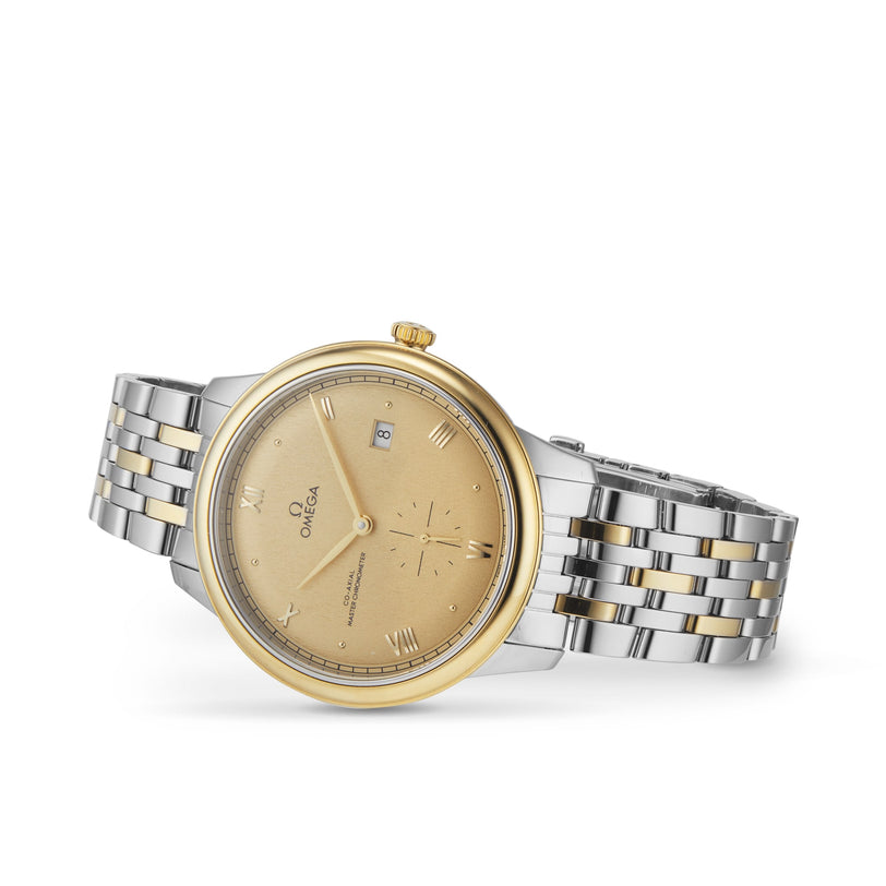 The OMEGA De Ville Prestige wristwatch features a two-tone gold bezel, gold dial, silver and gold bracelet, Roman numerals, date window at 3 oclock, subdial above 6 oclock, and the Omega Master Co-Axial 8802 movement.