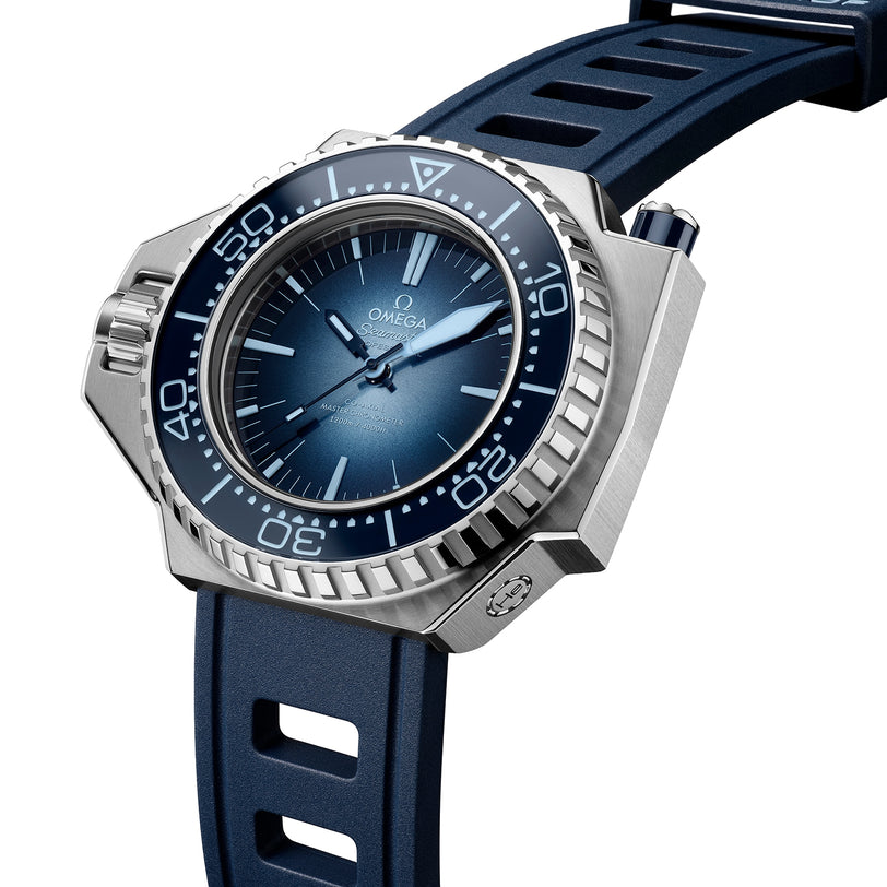 An OMEGA Seamaster Ploprof 1200M Summer Blue dive watch with a blue dial, blue bezel, blue rubber strap, and prominent crown guard is displayed at an angle.
