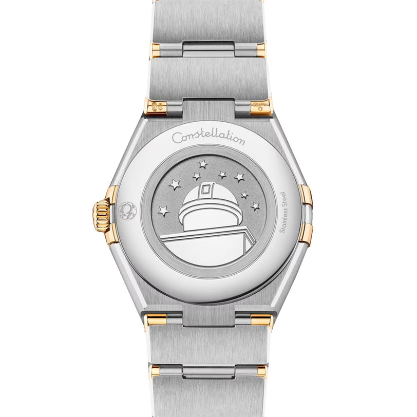 A close-up of the OMEGA Constellation’s caseback in stainless steel and 18K yellow gold, featuring the engraved observatory, stars, and Constellation inscription.