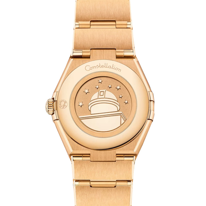 Close-up of the back of an OMEGA Constellation watch in 18K yellow gold, showing an engraved observatory with stars and Constellation inscribed above.
