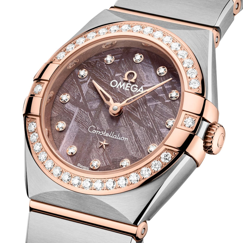 Close-up of the OMEGA Constellation wristwatch, showcasing a brown meteorite dial, diamond hour markers, and diamond-paved bezel in a blend of rose gold and stainless steel.