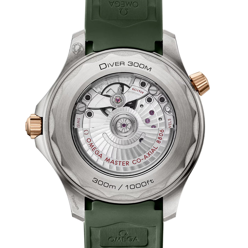 Close-up of the OMEGA Seamaster Diver 300M case back, showing its exposed Co-Axial Master Chronometer movement, “Diver 300M” and “Omega Master Co-Axial 8800” engravings, and a green strap.