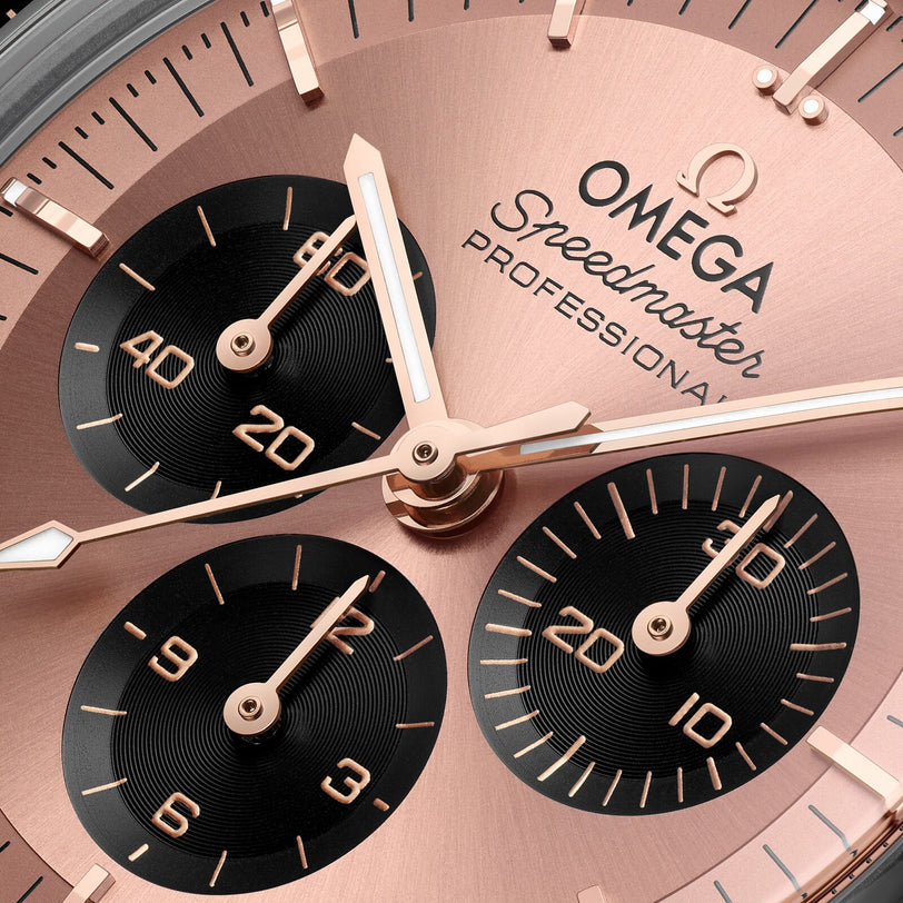 Close-up of an OMEGA Speedmaster Moonwatch face with rose gold details, featuring three subdials and bold hour and minute hands.