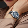 A person wearing a Raymond Weil Freelancer Automatic Blue Dial watch with a sunrayed blue dial and metal band, resting their hand on their neck.