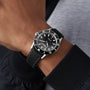 A person wearing the Raymond Weil Freelancer Diver Black Dial wristwatch, featuring a minimalistic black dial with white markers, rotating bezel, black strap, and precise timekeeping—ideal for affordable luxury seekers.