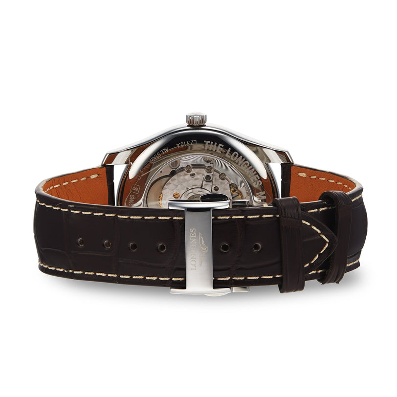 A close-up rear view of the Longines Master Collection watch shows its L897.2 calibre movement, brown leather strap, and Longines-engraved clasp.