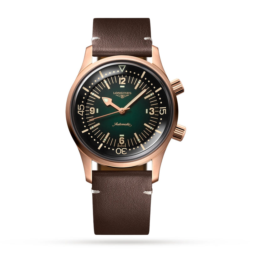 The Longines Legend Diver Bronze features a bronze case, dark green dial with beige Super-LumiNova markings, dual crowns, and a brown leather strap, all shown on a white background.