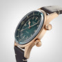 The Longines Legend Diver Bronze wristwatch features a teal dial with white Super-LumiNova markers, two crowns, and a black leather strap, displayed against a neutral background.