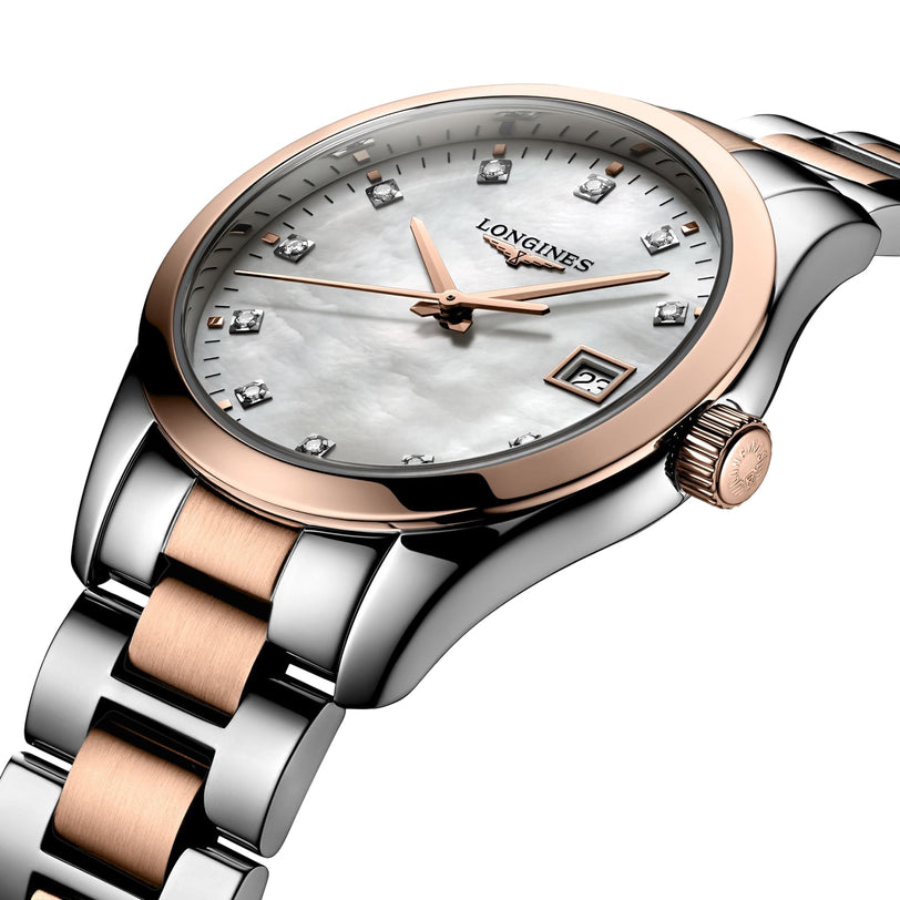 The Longines Conquest Classic features a silver and rose gold case, white mother-of-pearl dial with diamond hour markers, quartz movement, date at 3 o’clock, and signature Longines branding.