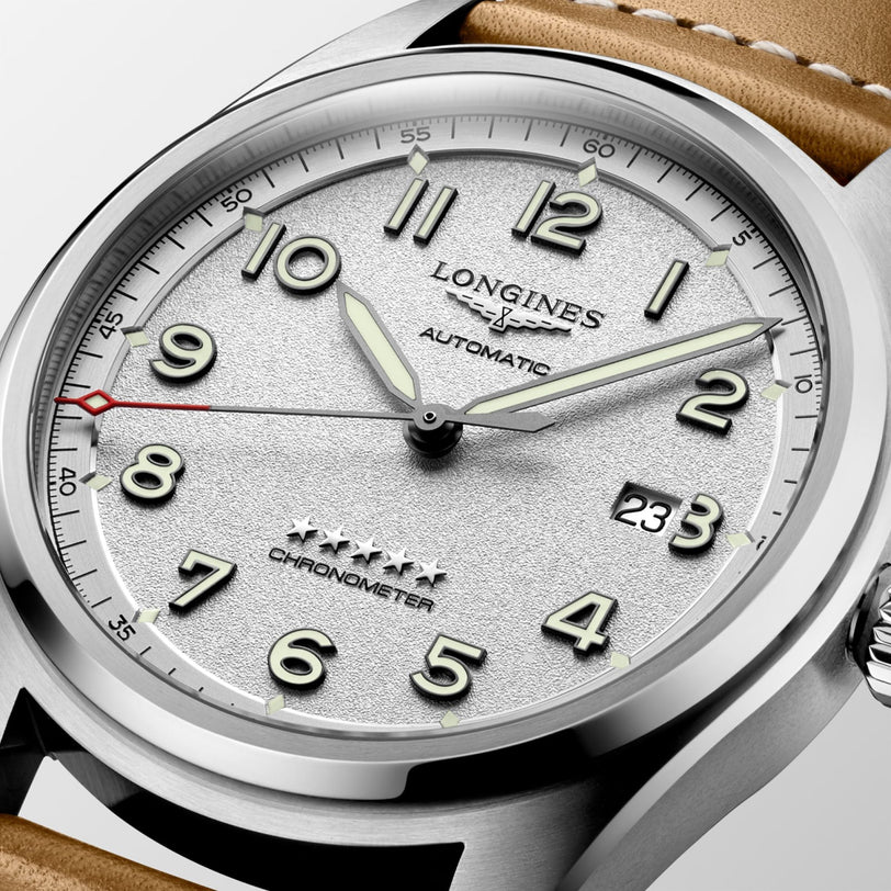 Close-up of the Longines Spirit automatic chronometer, featuring a textured silver dial with Arabic numerals, luminescent hands, date display, and a brown leather strap—capturing the pioneering heritage of the Longines Spirit collection.