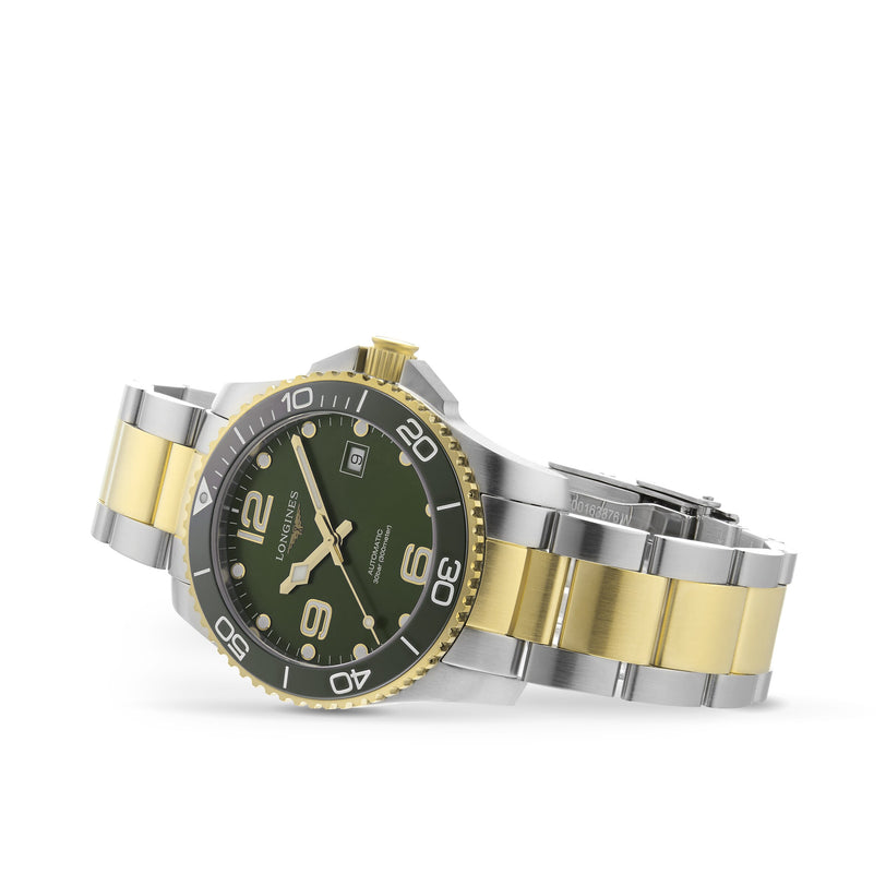 The Longines HydroConquest is a stainless steel and gold diving watch featuring a green dial, rotating bezel, and date display, shown at an angle to highlight both the bracelet and the watch face.