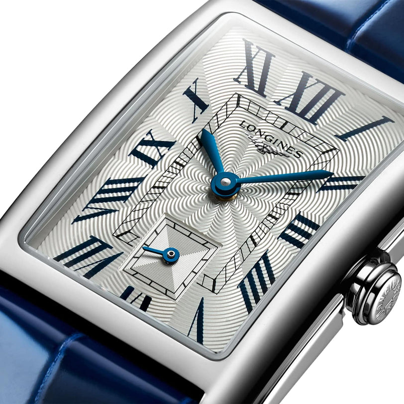 Close-up of a Longines DolceVita watch with a stainless steel case, patterned dial, blue Roman numerals and hands, and a blue leather strap.