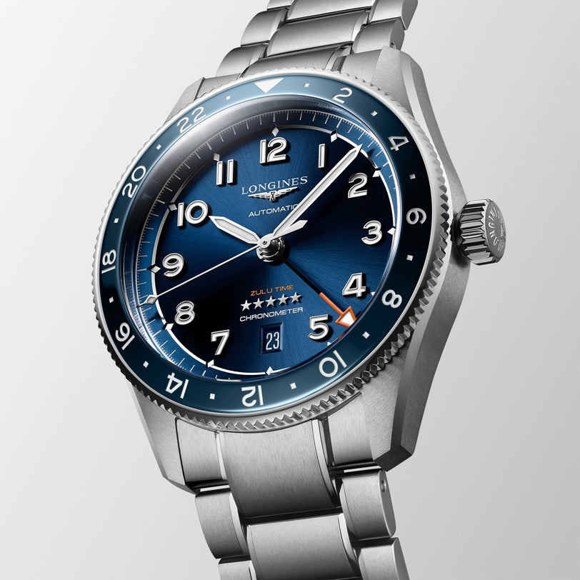 The Longines Spirit Zulu Time is a stainless steel wristwatch featuring a blue dial, silver hour markers, and a metal bracelet.