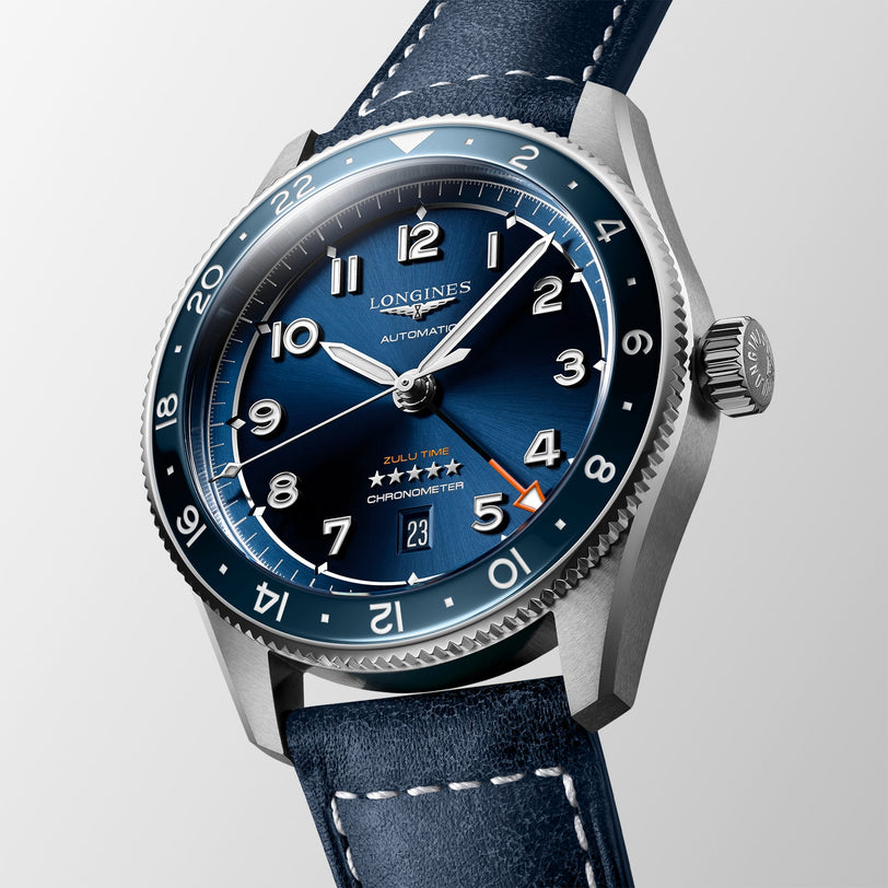 The Longines Spirit Zulu Time features a blue dial with silver numerals, date at 6 o’clock, blue ceramic 24-hour bezel, stainless steel case, and a blue leather strap.