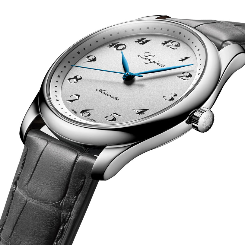 A Longines Master Collection silver analog wristwatch with blue hands, black Arabic numerals, a gray leather strap, and a silicon balance-spring is elegantly displayed—an exclusive piece for discerning collectors.