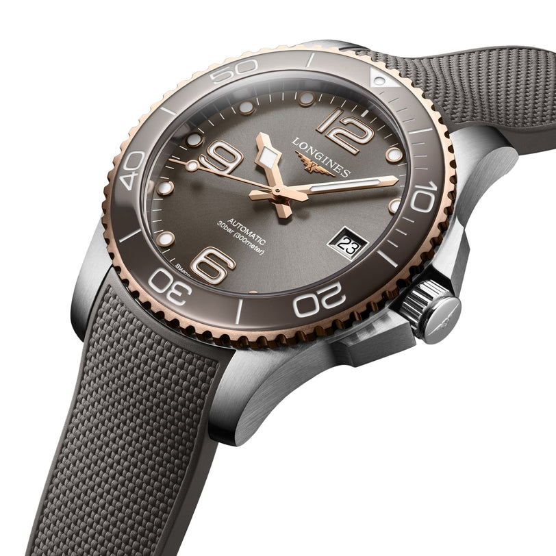 A close-up of the Longines HydroConquest, an automatic wristwatch with grey textured strap, bronze bezel, grey dial, Swiss Super-LumiNova markers, date at 3 o’clock, and water-resistant craftsmanship.